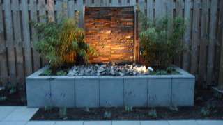 tuin bij avond met een spot op het moderne waterelement